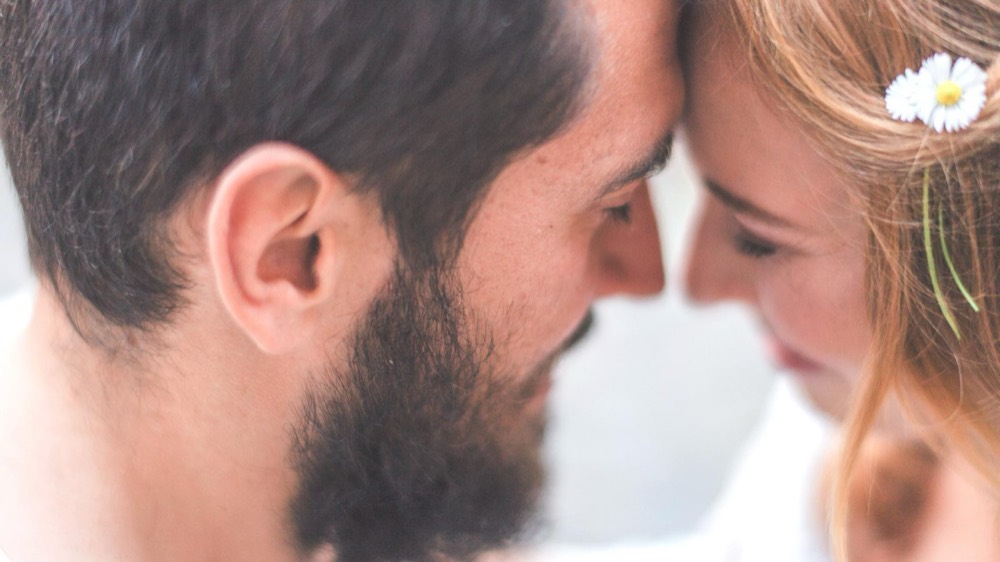 Los novios frente con frente, con flores en el pelo