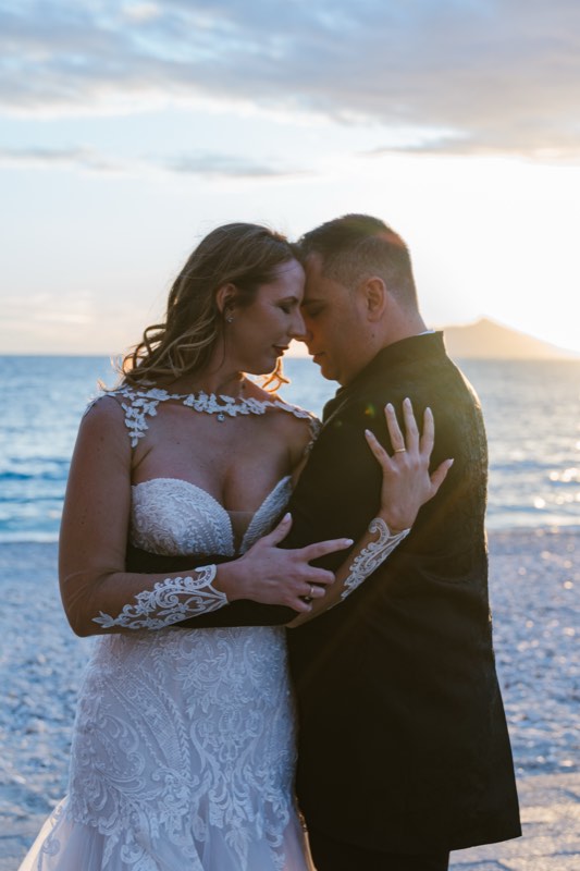 Los novios abrazados en la playa al atardecer