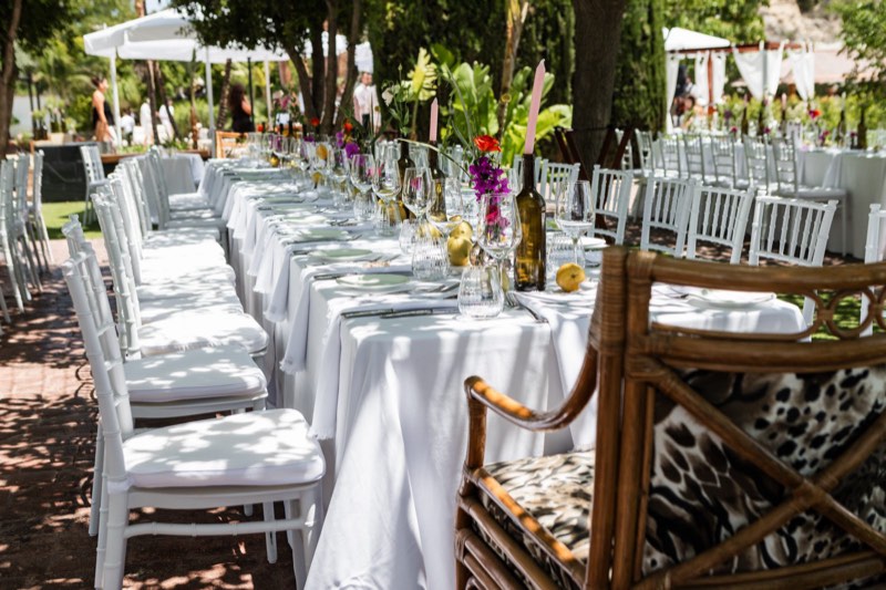 Mesa larga de banquete con sillas blancas y flores